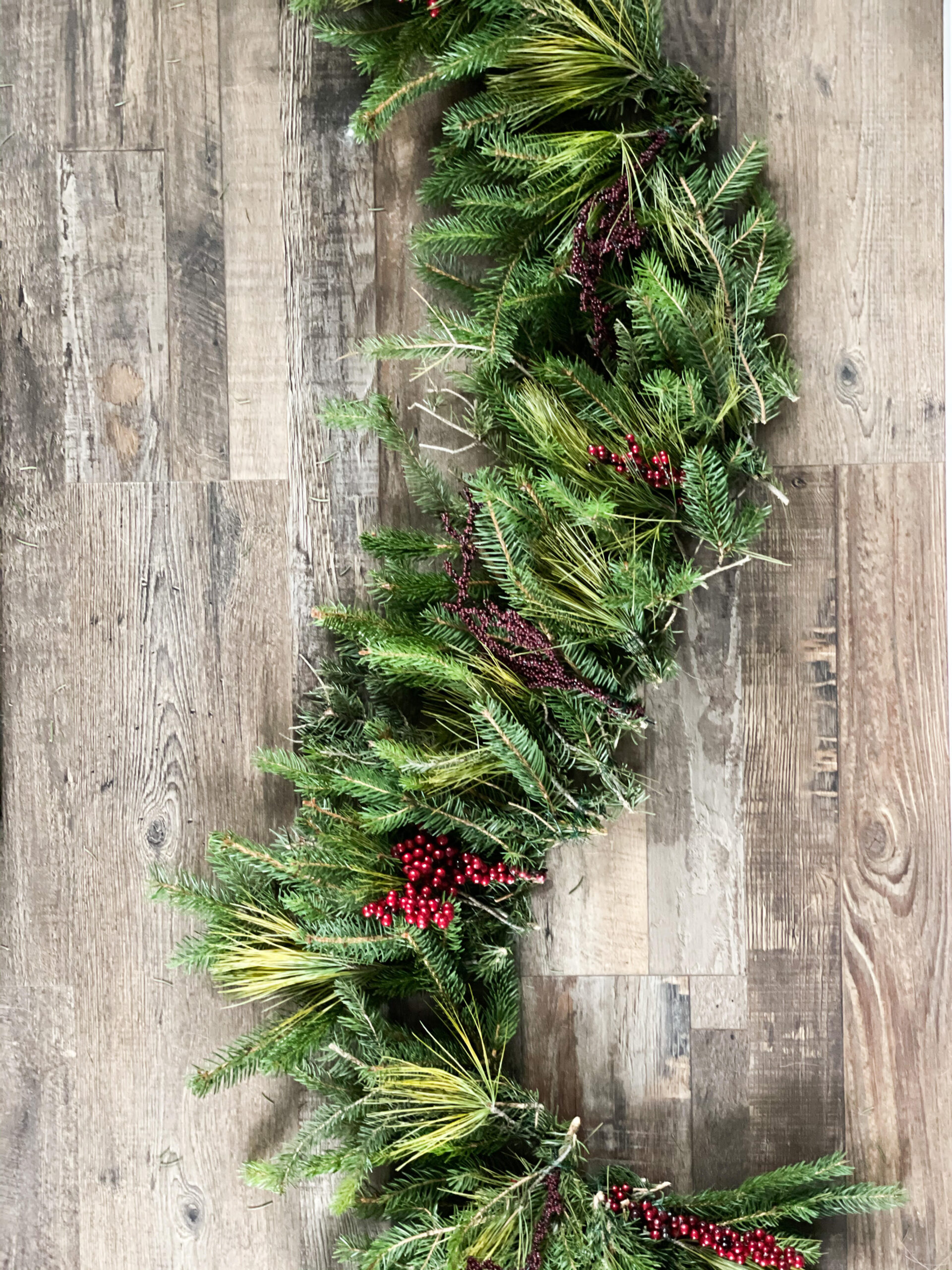 Real pine made into garland with red berries laying on the ground 