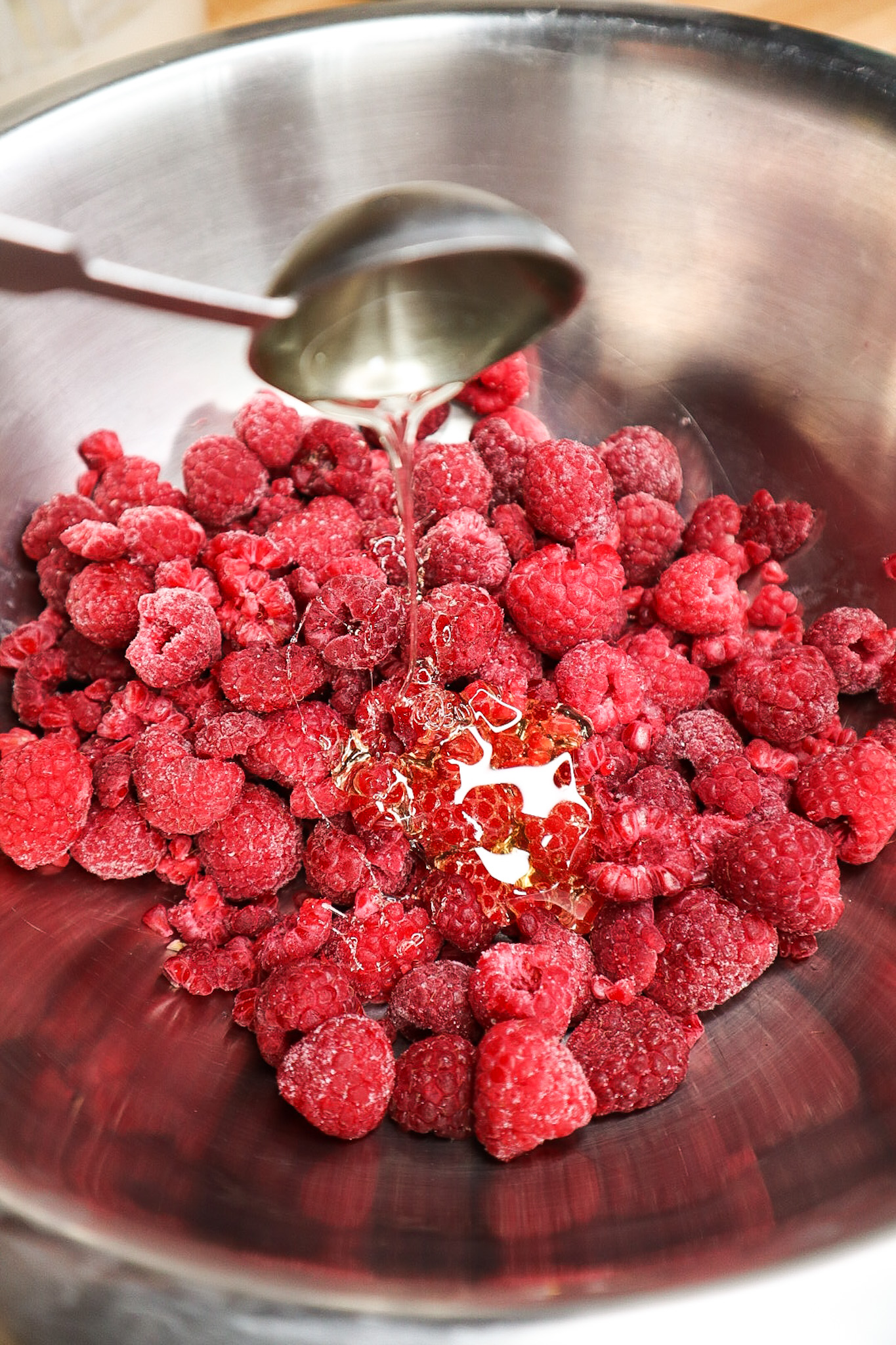 Raspberries in a bowl pouring honey 