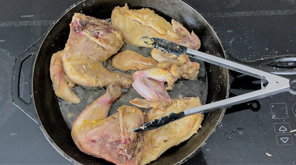 chicken cuts frying in a cast iron skillet 